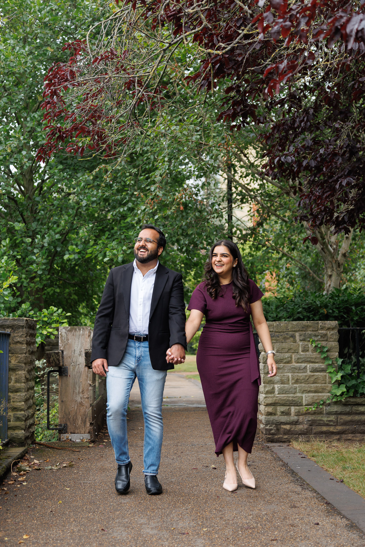 Couple walking hand in hand during Oxford engagement photography session on cobblestone streets