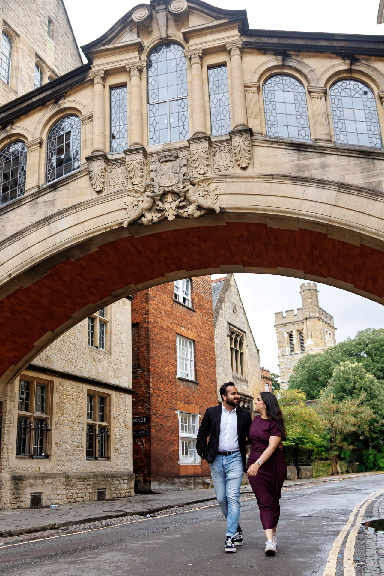 Couple walking hand in hand on Oxford cobblestone streets during engagement session